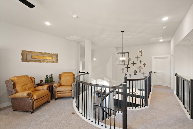 living area featuring an upstairs landing, recessed lighting, light carpet, and an inviting chandelier