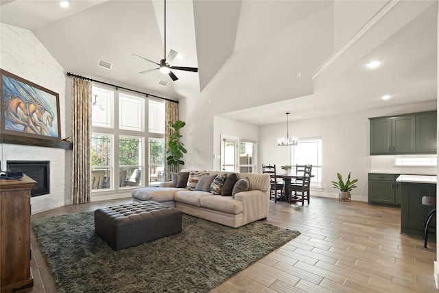 living room featuring visible vents, recessed lighting, a stone fireplace, ceiling fan with notable chandelier, and light wood-type flooring