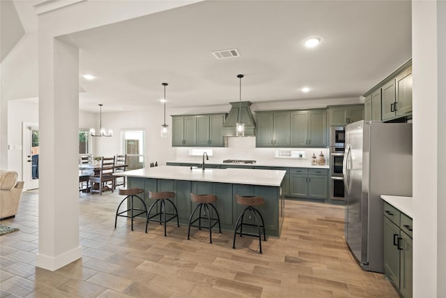 kitchen with visible vents, light countertops, custom range hood, stainless steel appliances, and a sink