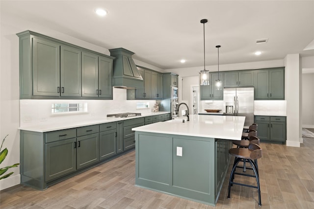 kitchen with visible vents, stainless steel appliances, green cabinets, and custom range hood