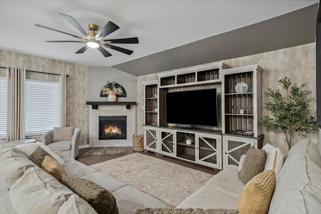 living room featuring a glass covered fireplace, a ceiling fan, and vaulted ceiling