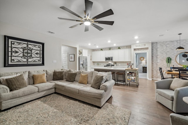 living room featuring visible vents, wallpapered walls, recessed lighting, ceiling fan, and wood-type flooring