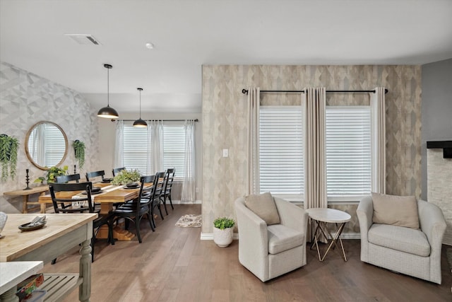 interior space with wallpapered walls, light wood-style flooring, visible vents, and baseboards