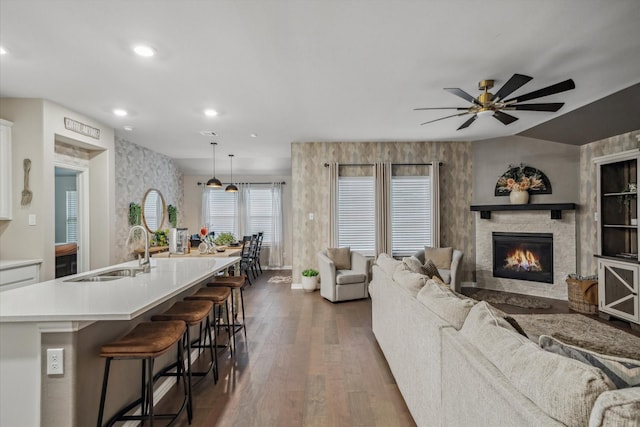 living room featuring a glass covered fireplace, recessed lighting, dark wood-style flooring, and ceiling fan