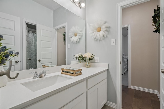 full bathroom featuring baseboards, wood finished floors, and vanity