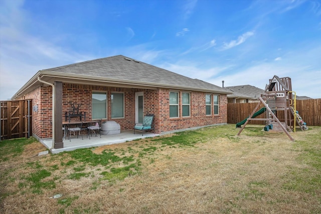 rear view of house featuring a fenced backyard, a lawn, a playground, a patio area, and brick siding