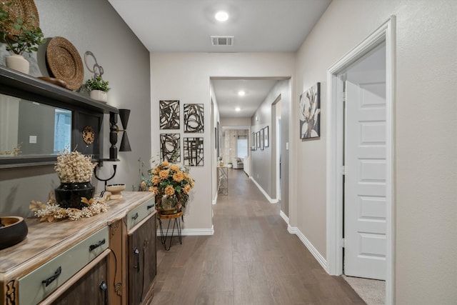 corridor with baseboards, visible vents, and dark wood-style flooring