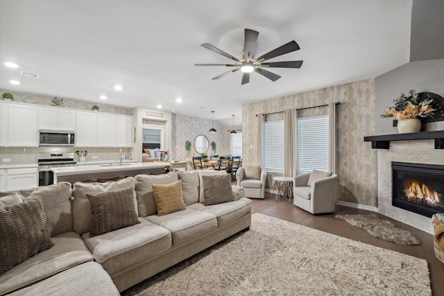 living room with visible vents, a stone fireplace, recessed lighting, wood finished floors, and a ceiling fan