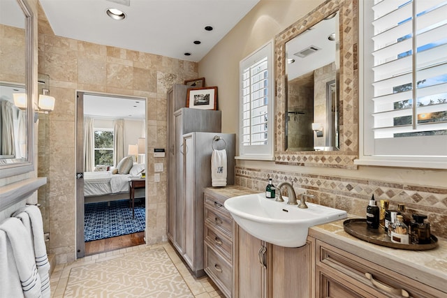 ensuite bathroom with backsplash, visible vents, ensuite bathroom, and a sink