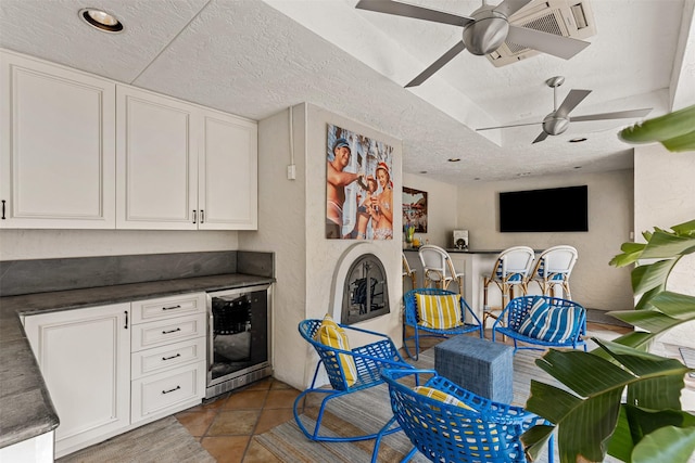 kitchen featuring dark countertops, beverage cooler, white cabinets, and a textured ceiling