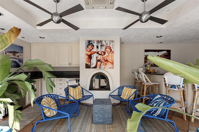 living area with visible vents, a textured ceiling, a dry bar, and a ceiling fan