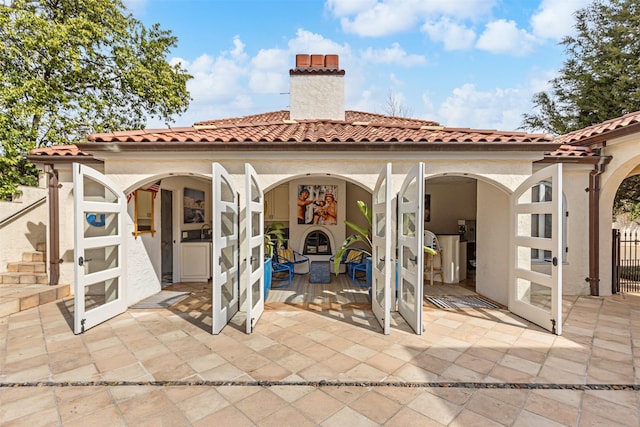 back of property featuring stucco siding, a tiled roof, and a chimney