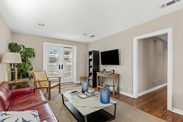 living room with wood finished floors, visible vents, french doors, and baseboards