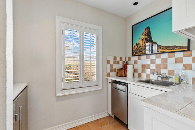 kitchen featuring tasteful backsplash, light tile patterned floors, white cabinetry, and a sink