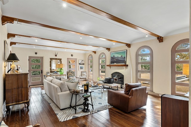 living room with a glass covered fireplace, hardwood / wood-style flooring, and beam ceiling