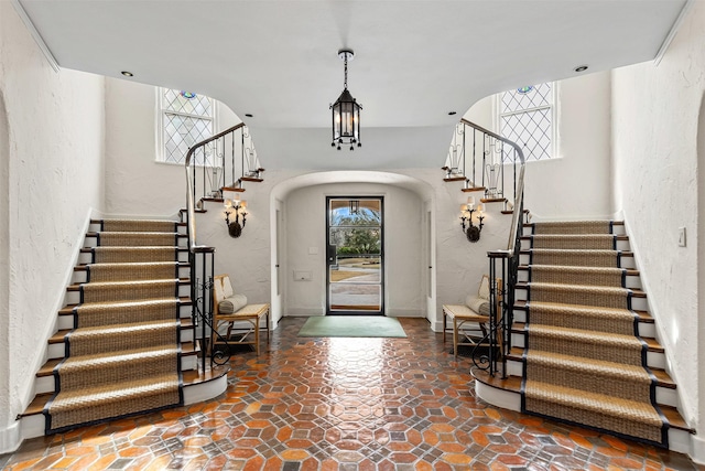 entrance foyer with arched walkways, stairs, and a textured wall