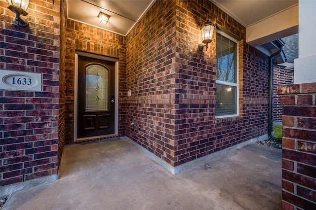 entrance to property with brick siding and a porch