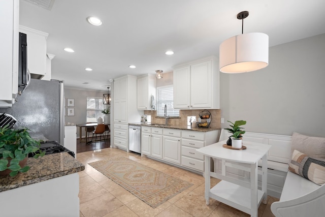 kitchen with recessed lighting, a sink, white cabinets, appliances with stainless steel finishes, and tasteful backsplash