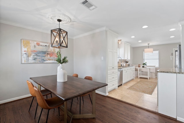 dining room featuring crown molding, baseboards, visible vents, and light wood-type flooring