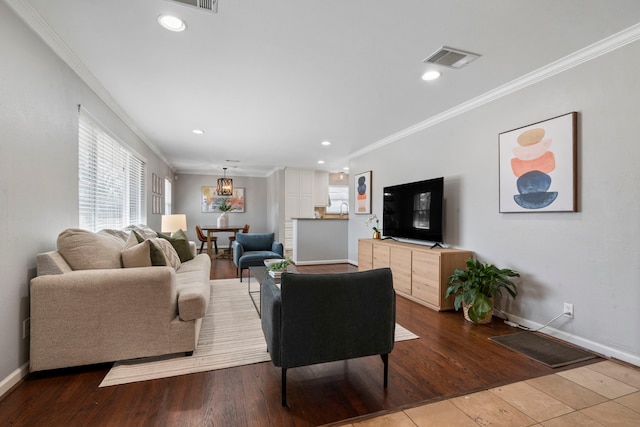 living room with crown molding, wood finished floors, baseboards, and visible vents