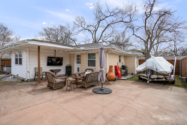 back of property with driveway, a patio, fence, an outdoor hangout area, and brick siding