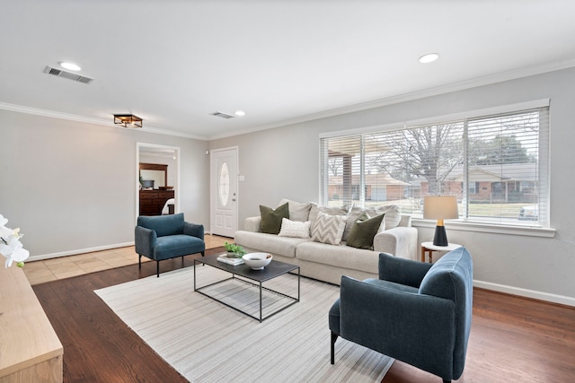 living area featuring visible vents, wood finished floors, baseboards, and ornamental molding