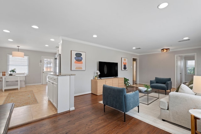 living area featuring crown molding, a healthy amount of sunlight, and visible vents