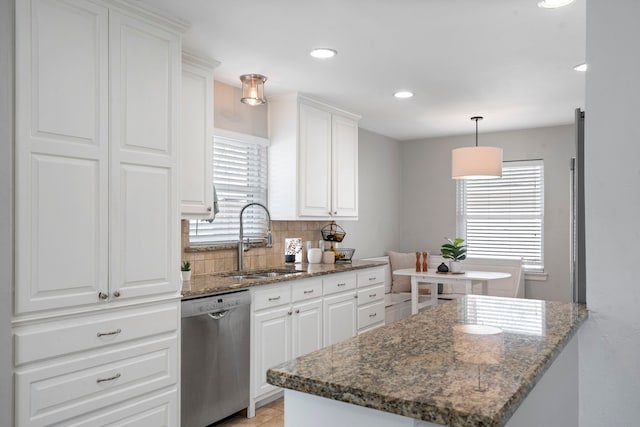 kitchen featuring tasteful backsplash, dishwasher, dark stone countertops, white cabinetry, and a sink