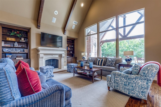 living area with beamed ceiling, built in shelves, high vaulted ceiling, a fireplace with raised hearth, and wood finished floors