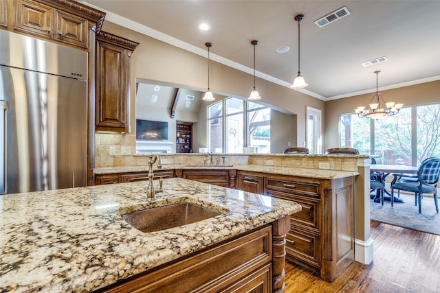 kitchen featuring wood finished floors, visible vents, a sink, ornamental molding, and high end refrigerator