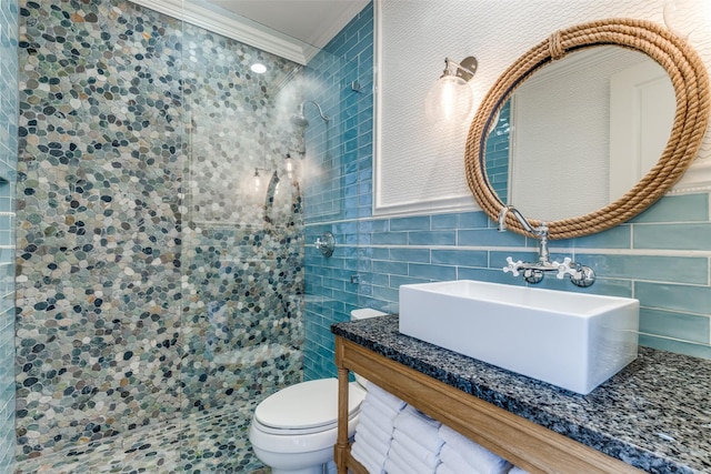 full bathroom featuring toilet, ornamental molding, a sink, tile walls, and tiled shower