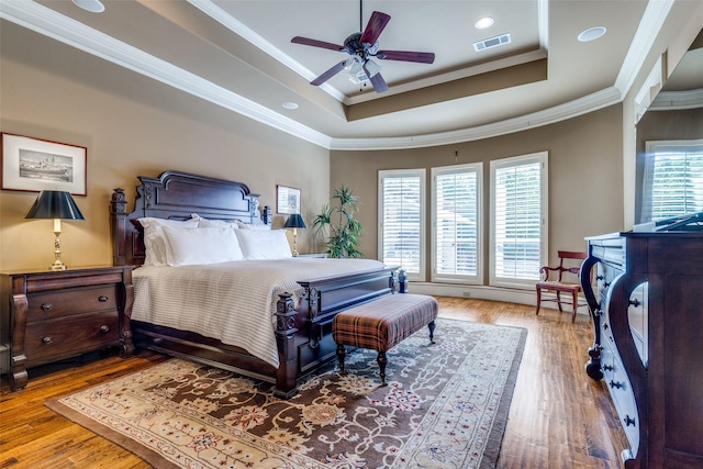 bedroom with visible vents, multiple windows, a raised ceiling, and hardwood / wood-style floors