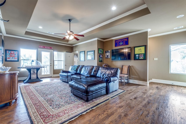 living area with visible vents, a raised ceiling, plenty of natural light, and wood finished floors