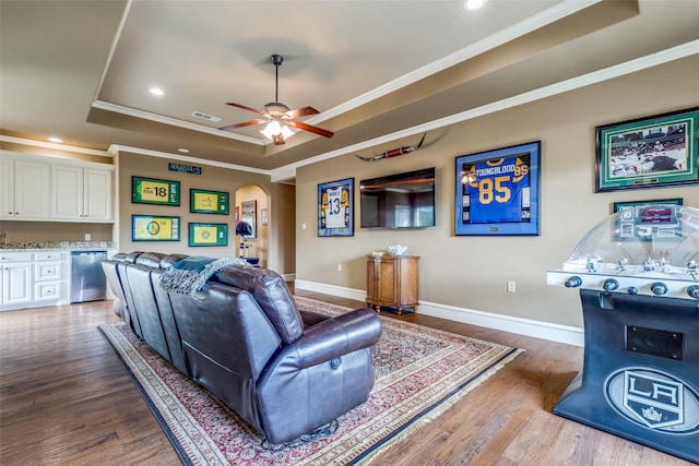 living area with a tray ceiling, crown molding, visible vents, and arched walkways