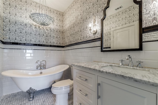 full bath featuring a freestanding tub, visible vents, toilet, tile walls, and vanity