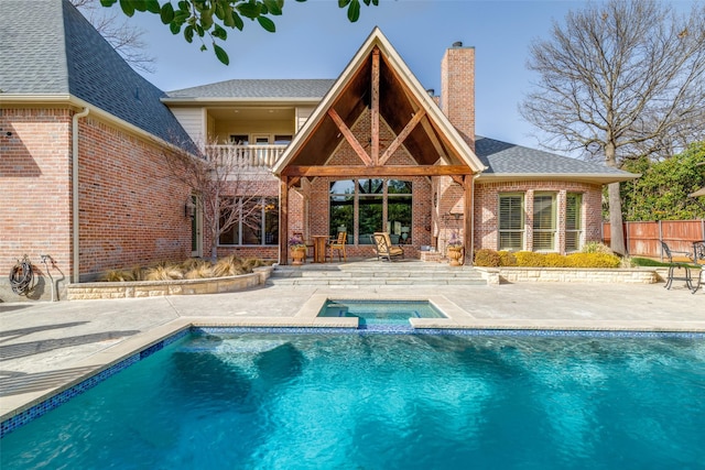 back of house with a patio, fence, brick siding, an in ground hot tub, and a chimney