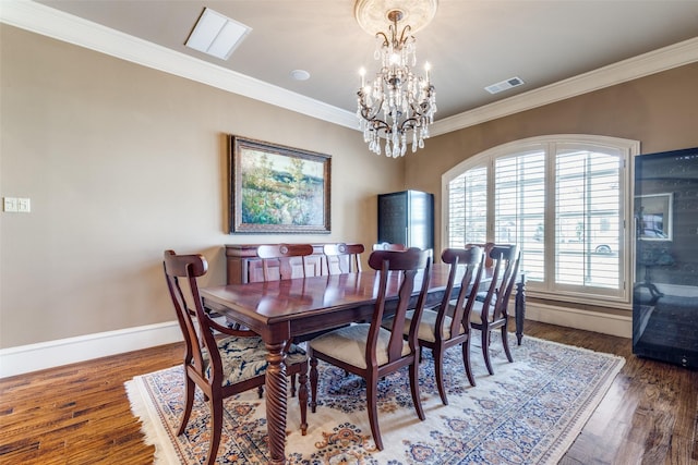 dining room with visible vents, ornamental molding, an inviting chandelier, and wood finished floors