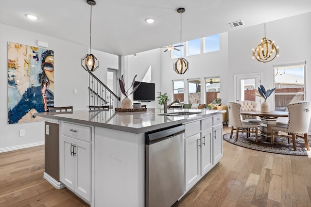 kitchen with visible vents, an island with sink, a sink, light wood-style floors, and dishwasher