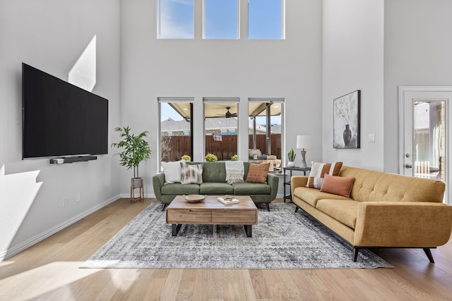 living area featuring baseboards, wood finished floors, and a towering ceiling