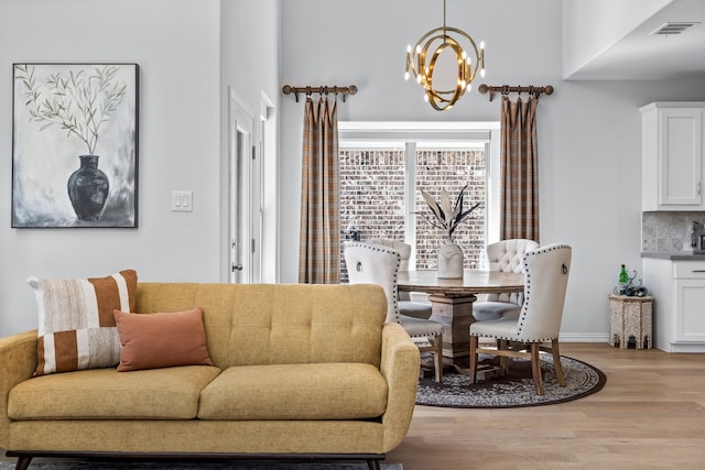 living room with a notable chandelier, visible vents, light wood finished floors, and baseboards