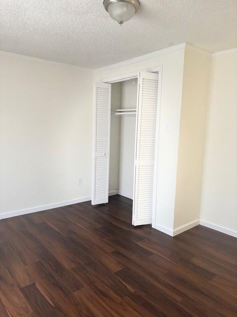 unfurnished bedroom featuring dark wood-style floors, a closet, and baseboards