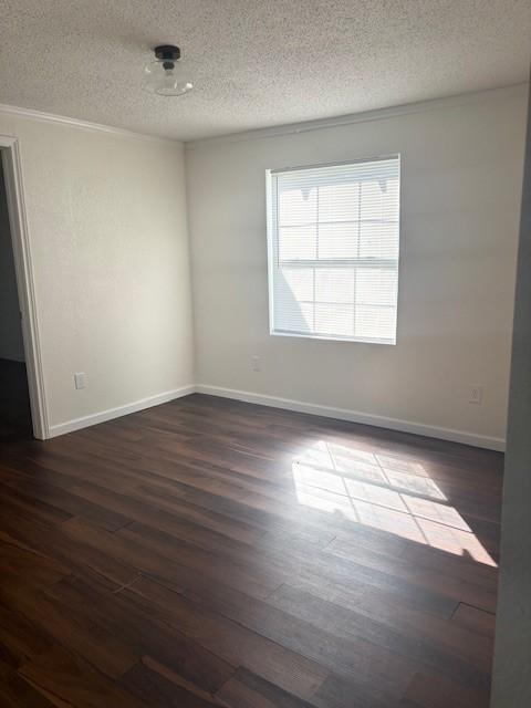 spare room featuring baseboards, dark wood-style flooring, and a textured ceiling