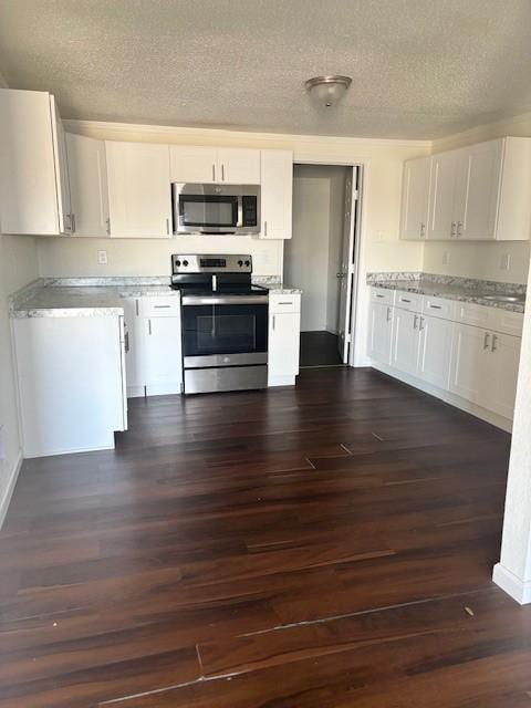 kitchen with a textured ceiling, white cabinetry, appliances with stainless steel finishes, baseboards, and dark wood-style flooring