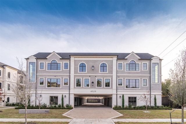 townhome / multi-family property with decorative driveway, a carport, and a front yard