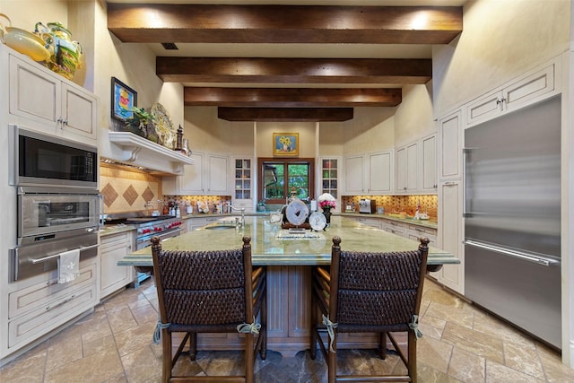 kitchen featuring stone tile flooring, built in appliances, tasteful backsplash, and a warming drawer