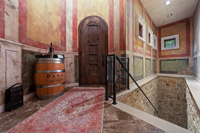 interior space with arched walkways, recessed lighting, marble finish floor, and wainscoting