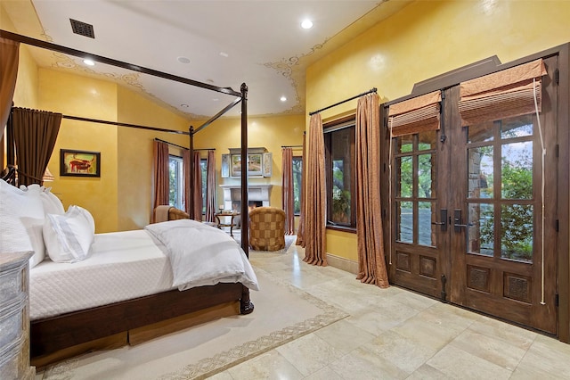 bedroom featuring visible vents, recessed lighting, a warm lit fireplace, vaulted ceiling, and french doors