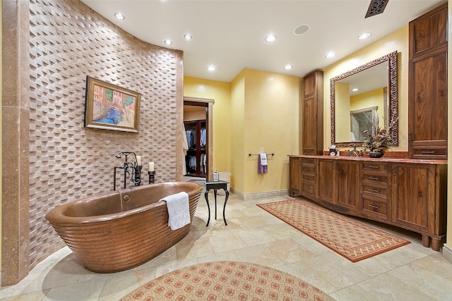 bathroom with visible vents, baseboards, recessed lighting, a freestanding tub, and vanity