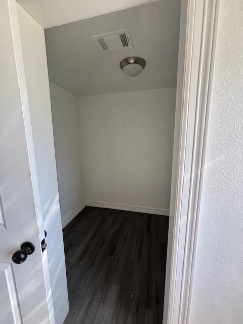 empty room with dark wood finished floors, baseboards, and visible vents