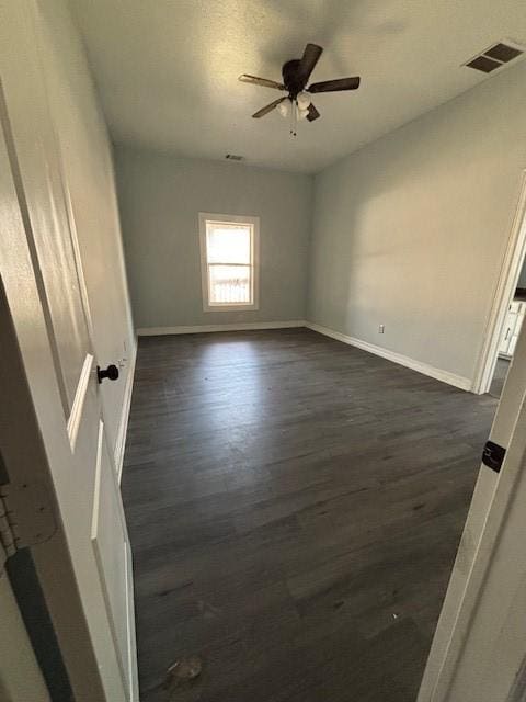 unfurnished bedroom featuring ceiling fan, visible vents, baseboards, and dark wood-style floors